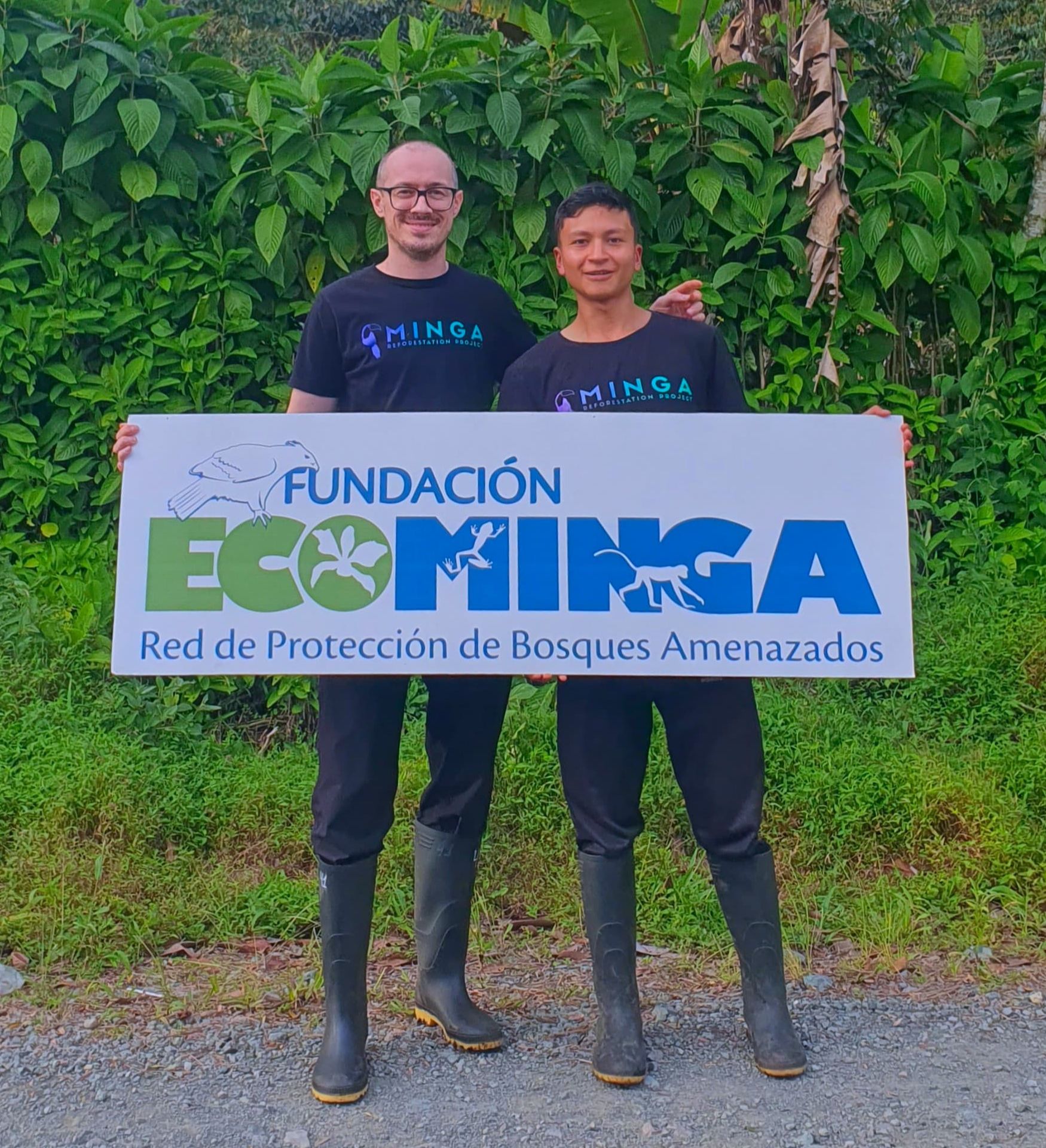 Kenzo van Gogh vom Minga Reforestation Project und Jhosué, Angestellter von Ecominga in Ecuador halten ein Plakat von Ecominga.